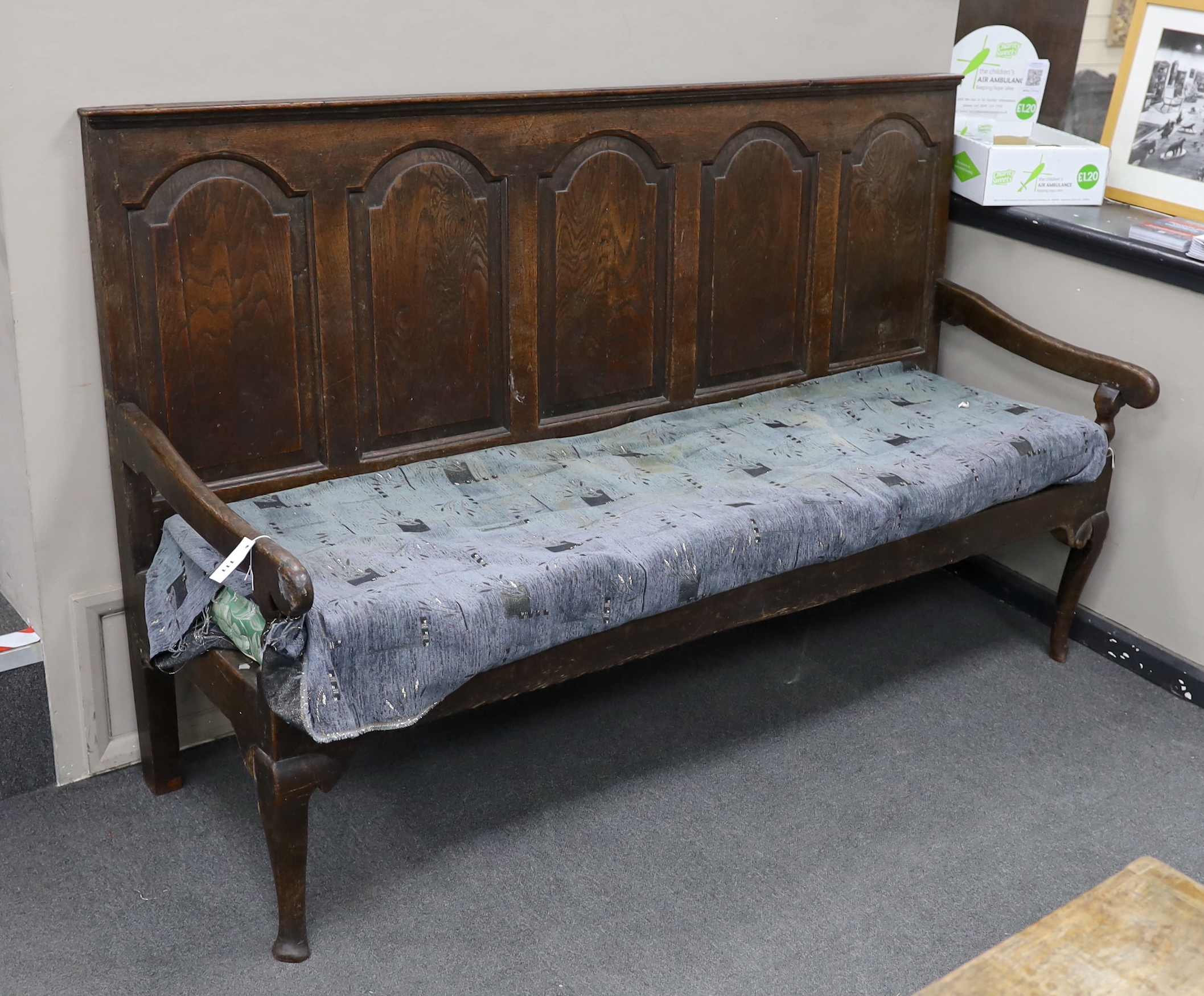 An 18th century panelled oak settle, with squab cushion seat, width 184cm, depth 65cm, height 112cm